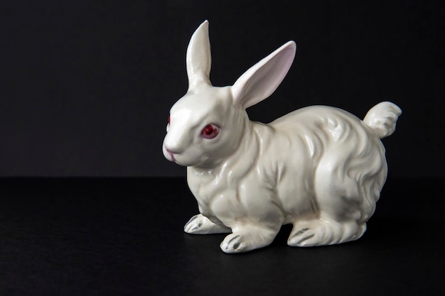 Coniglio in ceramica bianca su sfondo nero. Simbolo del coniglietto giocattolo dell'anno 2023