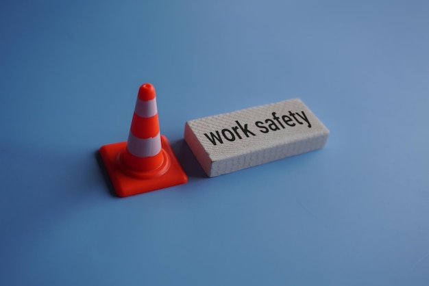 Conio di sicurezza stradale e testo SICUREZZA DEL TRAVEL su sfondo blu Concetto di sicurezza sul posto di lavoro