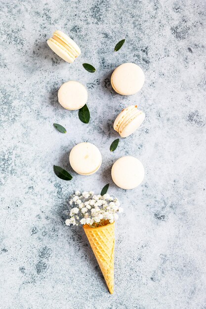 Cono di cialda ripieno di fiori di gipsofila e macarons con foglie Colori pastello