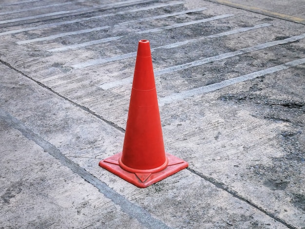 Cono di traffico stradale in plastica arancione sul pavimento di cemento