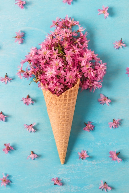 Cono gelato con fiori di primavera rosa ciliegia o fiori di sakura. Disteso. vista dall'alto. orientamento verticale