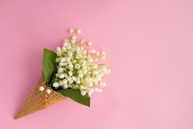 Cono gelato con mughetti sullo sfondo rosa.Vista dall'alto. Copia spazio. Concetto di fiori di primavera.