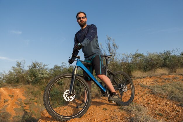 Conquista delle vette da ciclista in pantaloncini e maglia su una moderna bici hardtail in carbonio con a