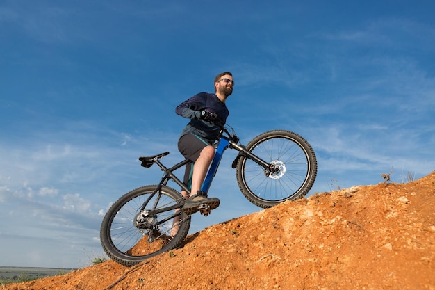 Conquista delle vette da ciclista in pantaloncini e maglia su una moderna bici hardtail in carbonio con forcella a sospensione pneumatica