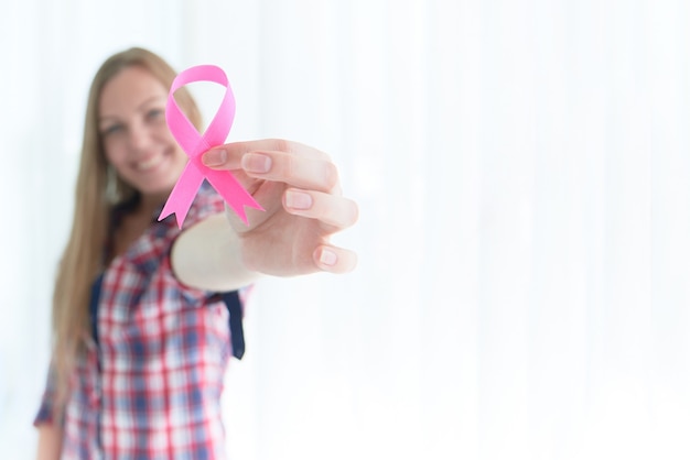 Consapevolezza del cancro al seno del nastro rosa della tenuta caucasica femminile bianca per il concetto di campagna del mese di consapevolezza del cancro al seno.