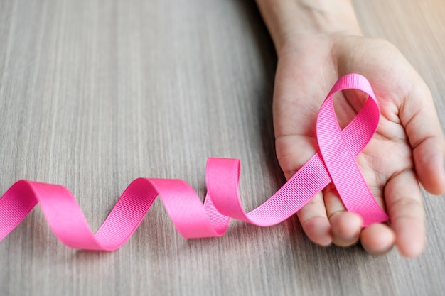 Consapevolezza del cancro al seno, mano della donna che tiene nastro rosa