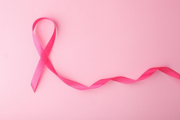 Consapevolezza sul cancro al seno con un nastro rosa su uno sfondo rosa