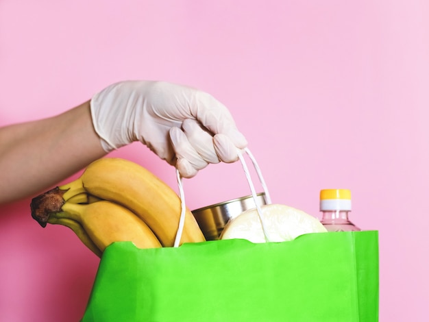 Consegna del cibo. Mani in guanti. Coronavirus. Sacco di carta con cibo