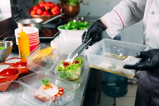 Consegna del cibo nel ristorante. Lo chef prepara il cibo nel ristorante e lo confeziona in piatti usa e getta.