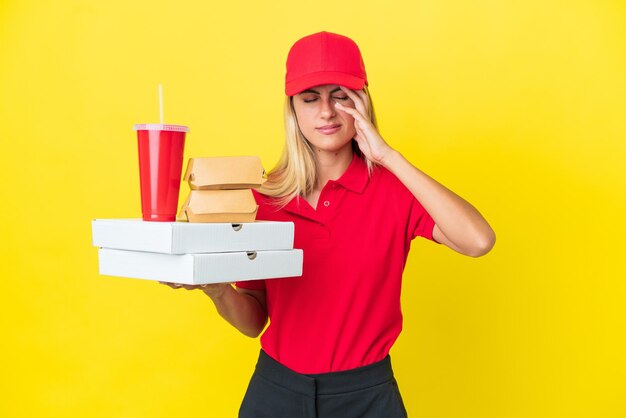 Consegna donna uruguaiana azienda fast food isolato su sfondo giallo con mal di testa