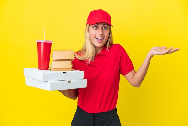 Consegna donna uruguaiana che tiene fast food isolato su sfondo giallo con espressione facciale scioccata