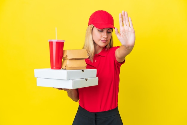 Consegna Donna uruguaiana che tiene un fast food isolato su sfondo giallo che fa un gesto di arresto e delusa