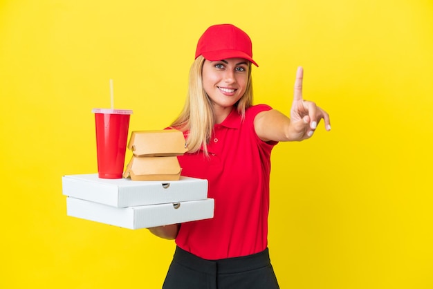 Consegna Donna uruguaiana che tiene un fast food isolato su sfondo giallo che mostra e alza un dito