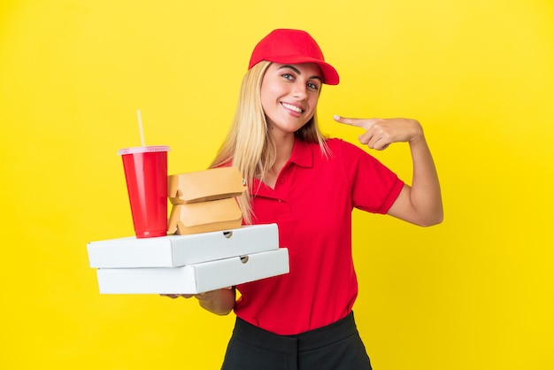 Consegna Donna uruguaiana che tiene un fast food isolato su sfondo giallo dando un pollice in alto gesto