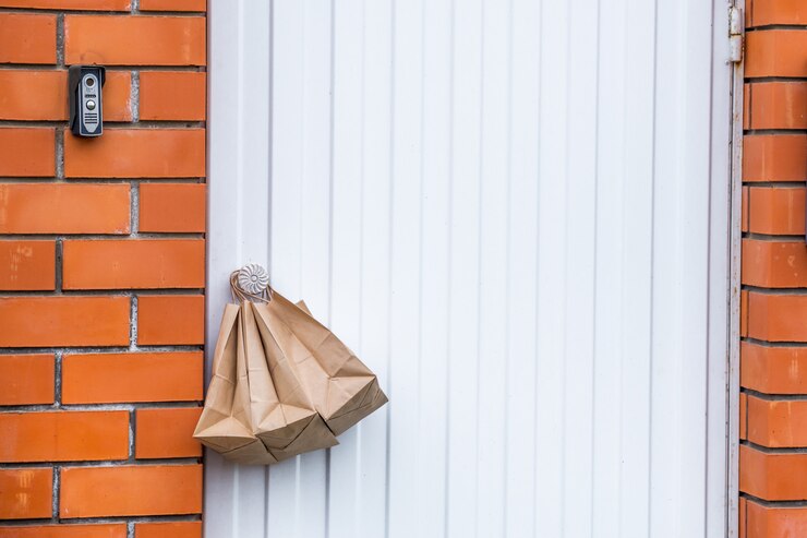 Consegna senza contatto sicura. sacchi di carta sulla maniglia della porta di casa. Ordine online. consegna senza contatto degli ordini in quarantena. Copia spazio.