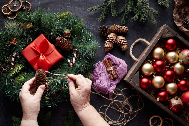 consegna una ghirlanda di Natale e decorazioni per l'albero su sfondo nero di cemento