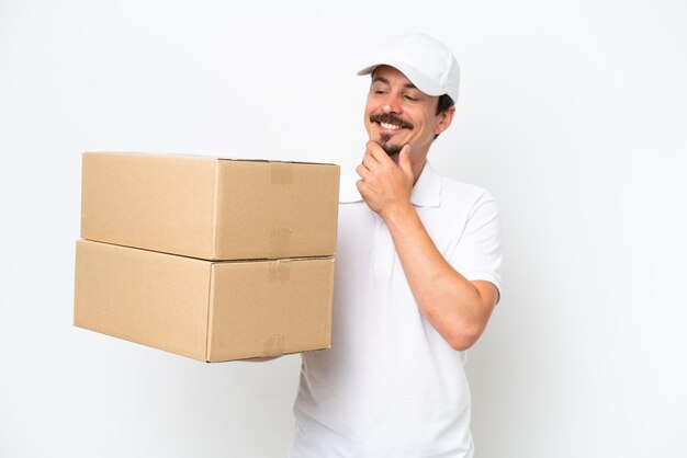 Consegna uomo caucasico isolato su sfondo bianco guardando al lato e sorridente