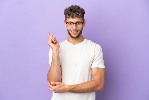 Consegna uomo caucasico isolato su sfondo viola felice e rivolto verso l'alto