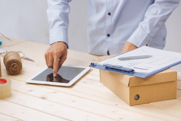 Consegnatore maschio con tablet sul posto di lavoro nell'ufficio postale