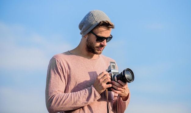 Consenti uno sguardo al futuro giornalista turistico uomo sexy cattura giornalista avventuroso uomo macho con fotocamera fotografo in occhiali viaggiare con fotocamera stile moda maschile alla moda
