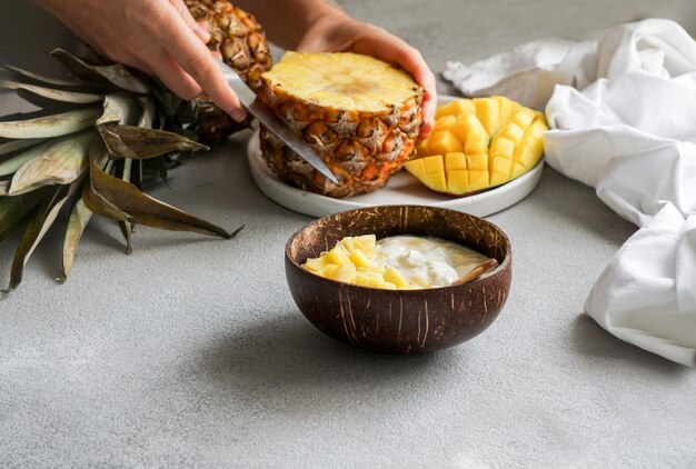 Consept sana colazione, yogurt con mango fresco e ananas nella ciotola di cocco