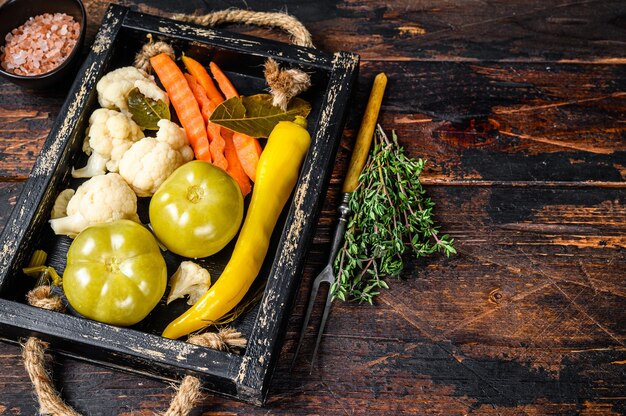 Conserva di verdure marinate e sottaceti fatte in casa su un vassoio di legno sul tavolo di legno. Vista dall'alto.