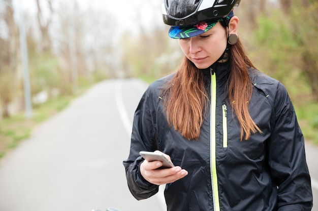 Considerato giovane donna nel casco da bicicletta tramite telefono cellulare in park