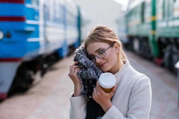 Consigli di viaggio. viaggio di vacanza turistica. vestiti comodi e comodi. accessori utili sciarpa. donna in una stazione ferroviaria