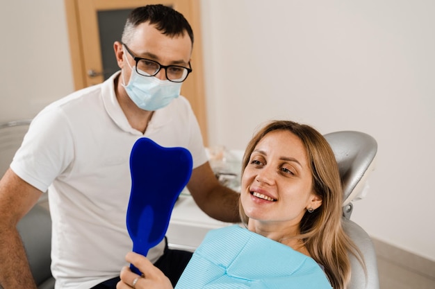 Consultazione con il dentista in odontoiatria Trattamento dei denti Donna che si guarda allo specchio dal dentista Paziente ragazza felice di odontoiatria