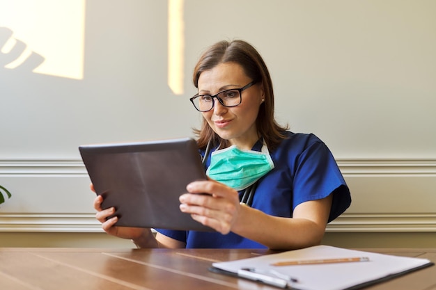 Consultazione online di un medico generico, donna che utilizza tablet digitale per videochiamate, medico che parla con il paziente. Telemedicina, assistenza sanitaria, concetto di persone