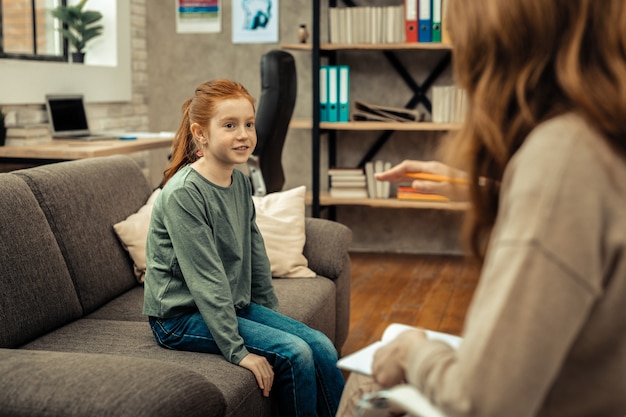 Consultazione psicologica. Ragazza carina e positiva che guarda il suo terapista mentre fa una consulenza psicologica