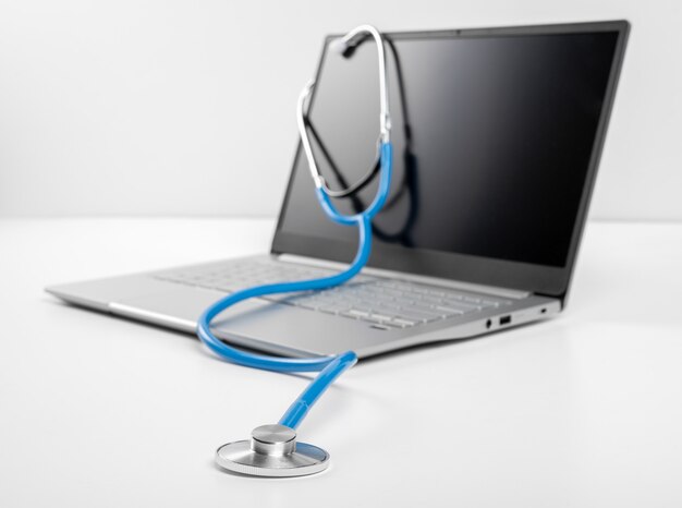 Consulto medico online, ospedale virtuale e terapia online. lo stetoscopio si trova sulla tastiera del laptop su sfondo bianco