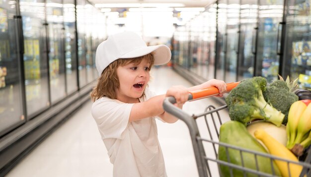 Consumismo di vendita e concetto di persone ragazzino felice con cibo nel carrello al negozio di alimentari