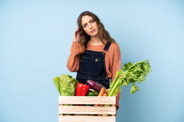 Contadino con verdure appena raccolte in una scatola con dubbi