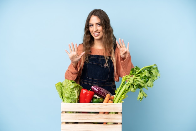 Contadino con verdure appena raccolte in una scatola contando nove con le dita