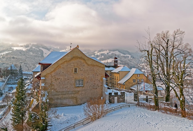 Contadino solitario in abiti cupi che torna a casa sotto un cielo nuvoloso. Gruyère, Svizzera