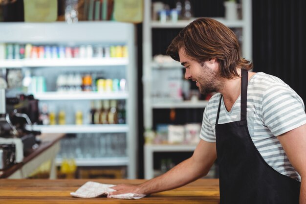 Contatore sorridente del caffè di pulizia del cameriere