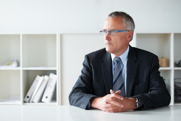 Contemplando la prossima mossa della sua azienda Colpo di un anziano uomo d'affari seduto a un tavolo