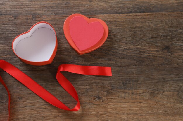 Contenitore di regalo a forma di cuore rosso sulla tavola di legno.