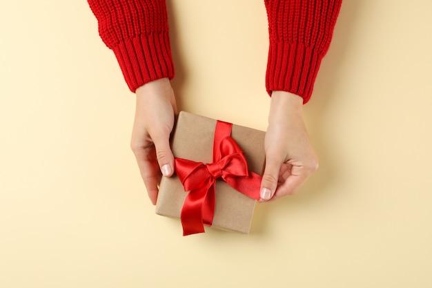 Contenitore di regalo della tenuta della giovane donna sul fondo di colore, spazio per testo