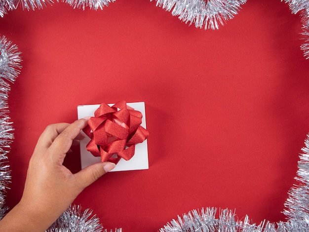 Contenitore di regalo della tenuta della mano della donna legato con il nastro rosso