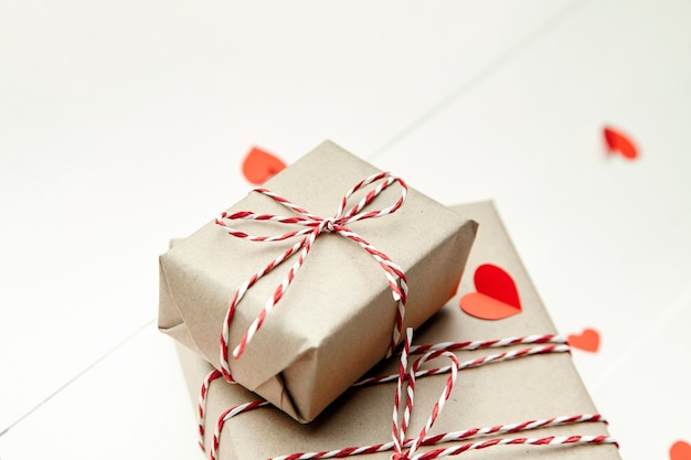 Contenitore di regalo di giorno di biglietti di S. Valentino e cuori di carta rossi sulla tavola di legno bianca