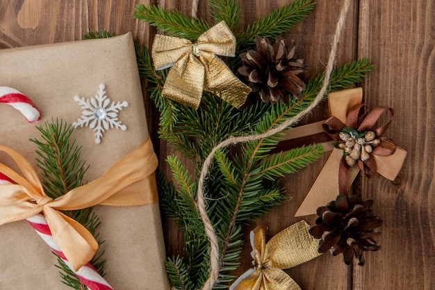 Contenitore di regalo di Natale, decorazione dell'alimento e ramo di abete sulla tavola di legno. Vista dall'alto con copyspace