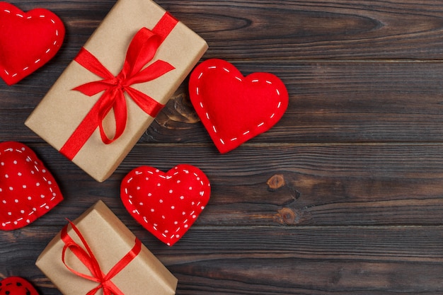 Contenitore di regalo e del cuore con il nastro rosso su fondo di legno