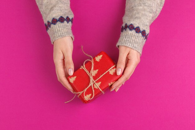 Contenitore di regalo in mani femminili su fondo rosa