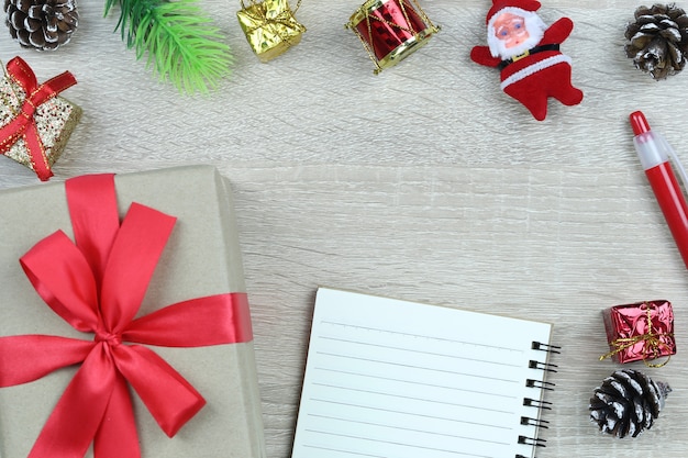 Contenitore di regalo marrone con fiocco rosso sul pavimento di legno e libro bianco in Natale e anno nuovo conce