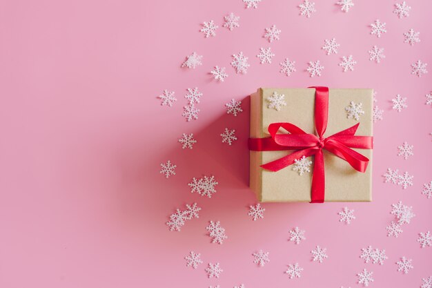 Contenitore di regalo marrone sullo sfondo rosa con decorazione di Natale.