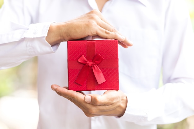 Contenitore di regalo rosso della stretta dell&#39;uomo di affari in mani.