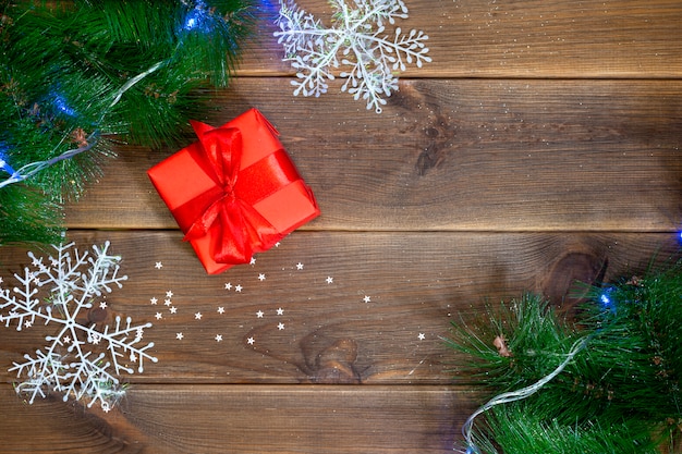 Contenitore di regalo su una tavola di legno, tavola con i rami del pino e palle rosse, concetto del nuovo anno