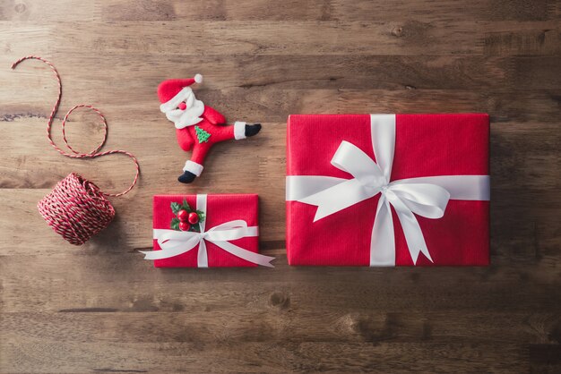 Contenitori di regalo rossi di Natale e oggetti di decorazione su fondo di legno